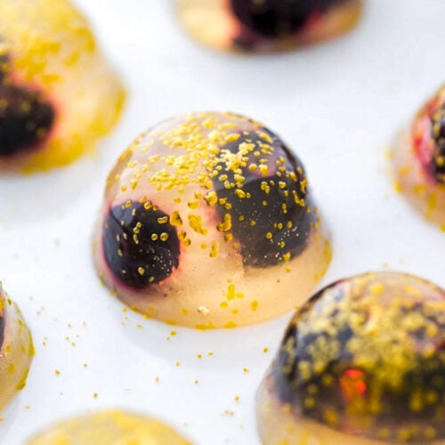 A close-up of a single champagne jello shot on a plate.