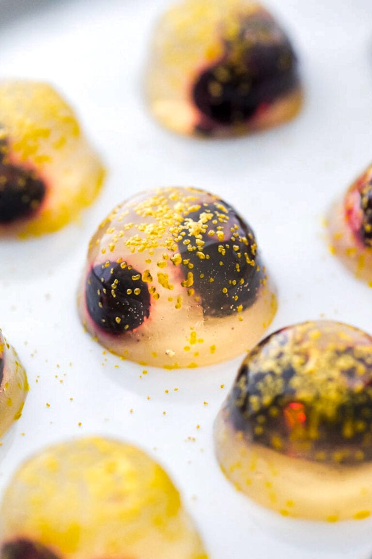 A close-up of a single champagne jello shot on a plate.