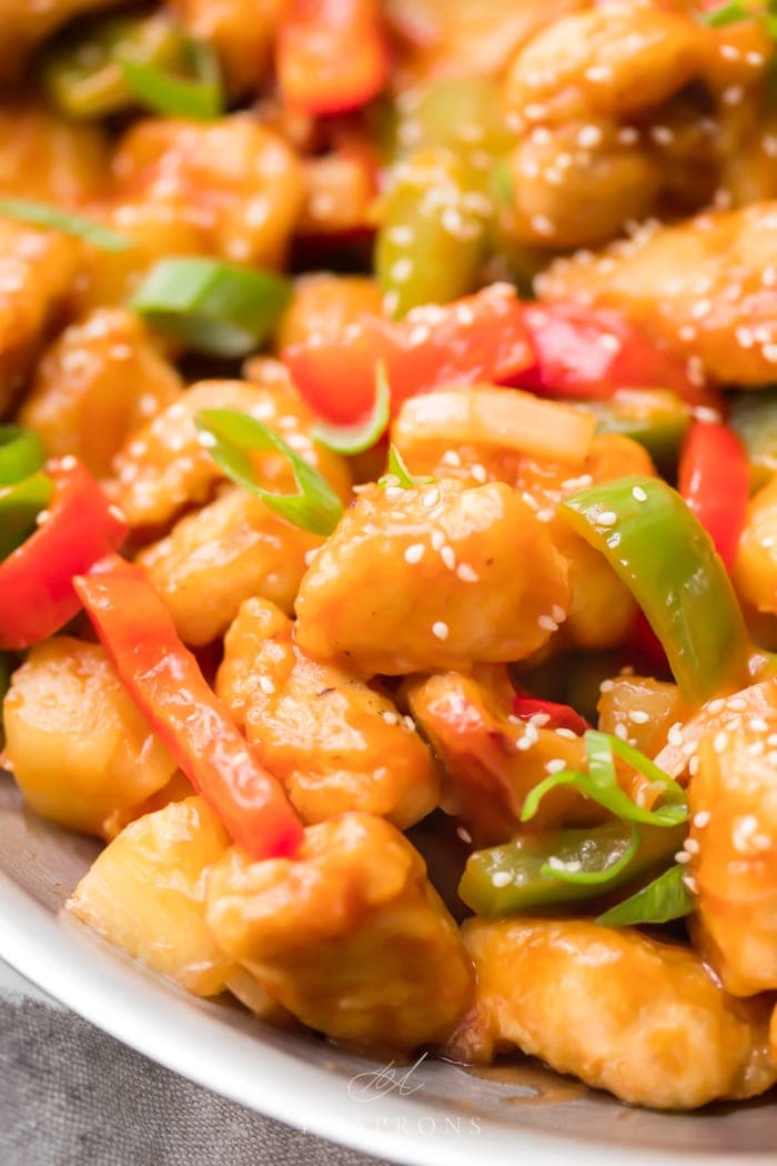 A skillet of healthy sweet and sour chicken with red and green bell peppers