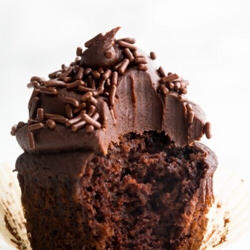 Closeup of chocolate paleo cupcake frosted with dark chocolate frosting with a bite taken out