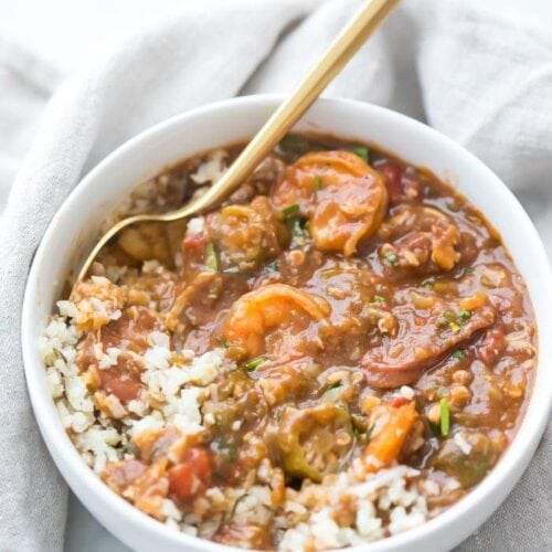 Healthy authentic seafood gumbo in a bowl with shhrimp and okra over cauliflower rice in a white bowl with gold spoon