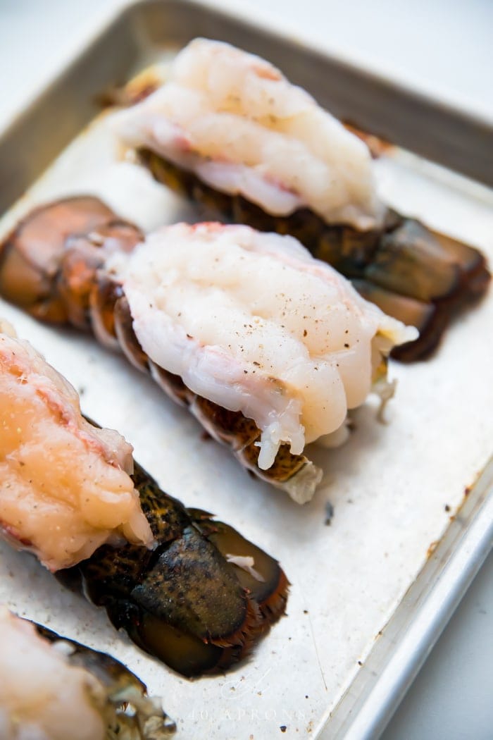 Butterflied lobster tails on a baking sheet