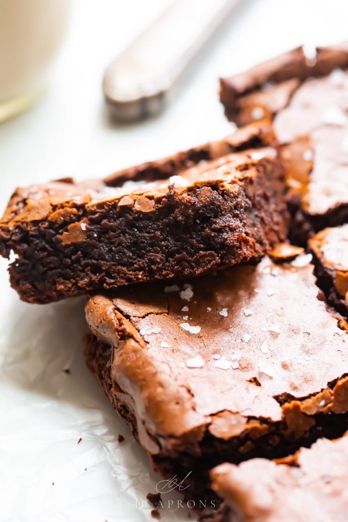 A batch of the best ever gluten brownies with one balanced on another, showing how fudgy it is with a crispy top