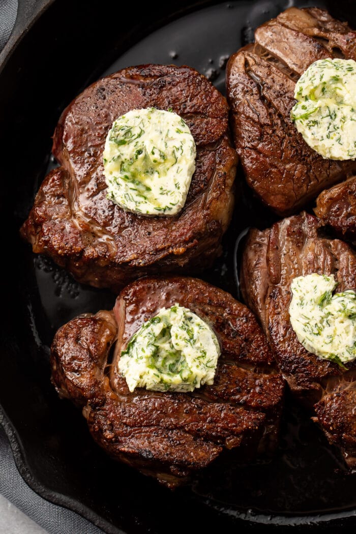 Extreme Close up of filet mignon topped with butter in a cast iron skillet