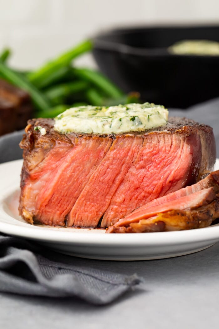 Close up of medium rare plated filet mignon topped with garlic herb butter