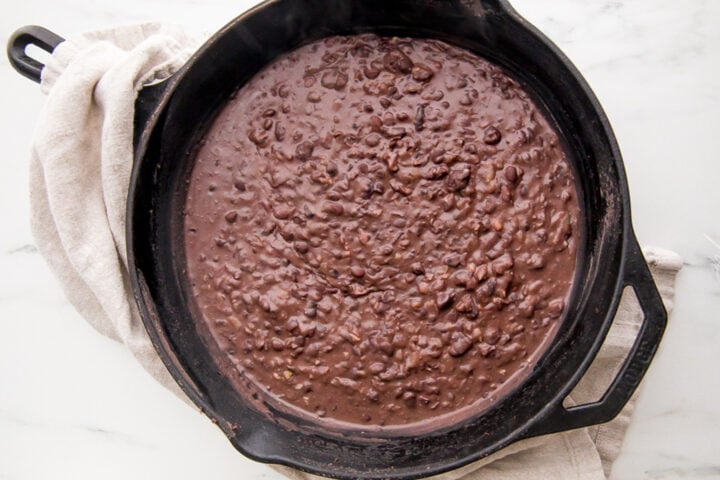 Refried black beans in a cast-iron skillet.