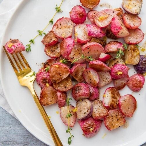 A white plate with roasted radishes on it