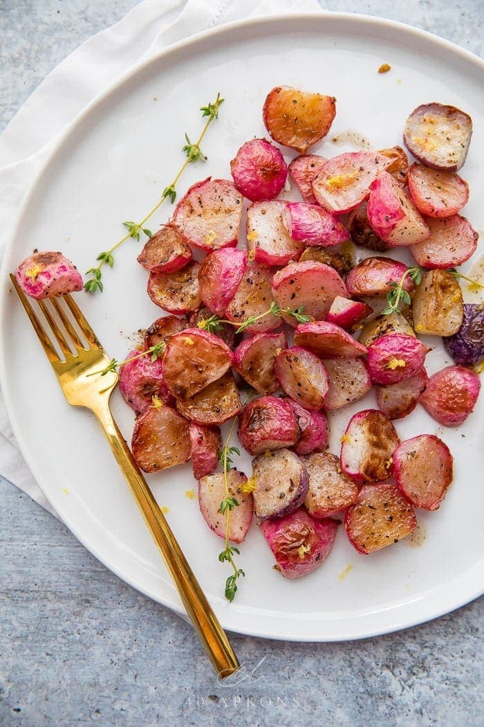 A white plate with roasted radishes on it