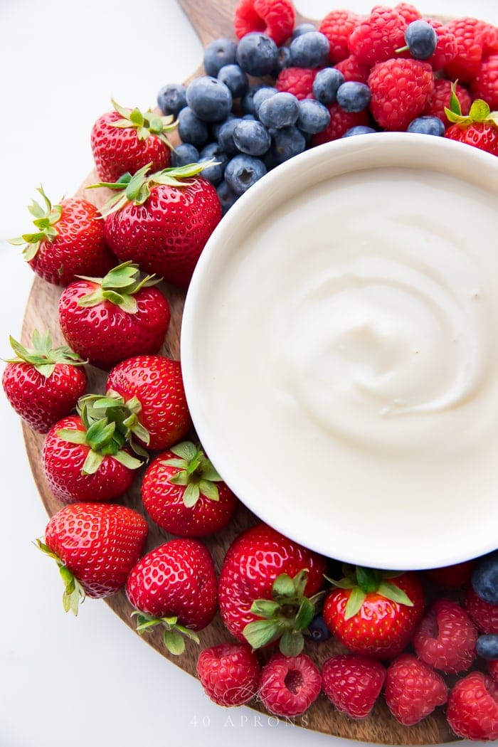 A tray of berries with bowl of yogurt fruit dip in the center