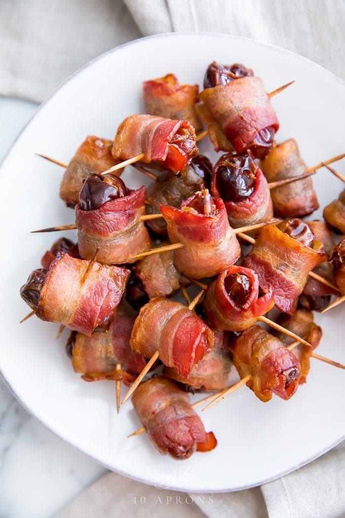 Bacon wrapped dates on a white plate