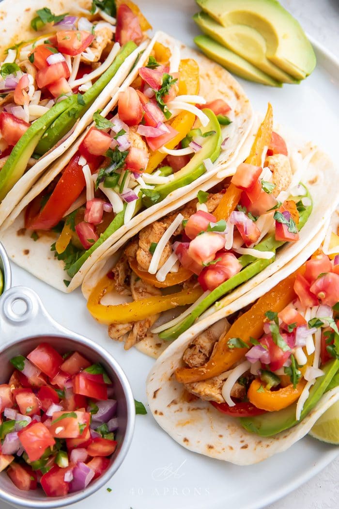 Tacos served on a white plate with salsa