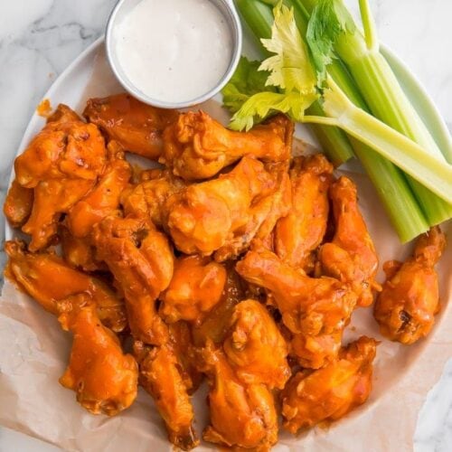 Crockpot chicken wings on parchment paper with celery and blue cheese