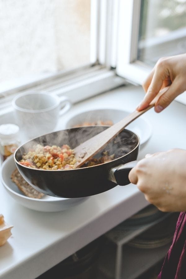 vegetables being sauteed in a black pan