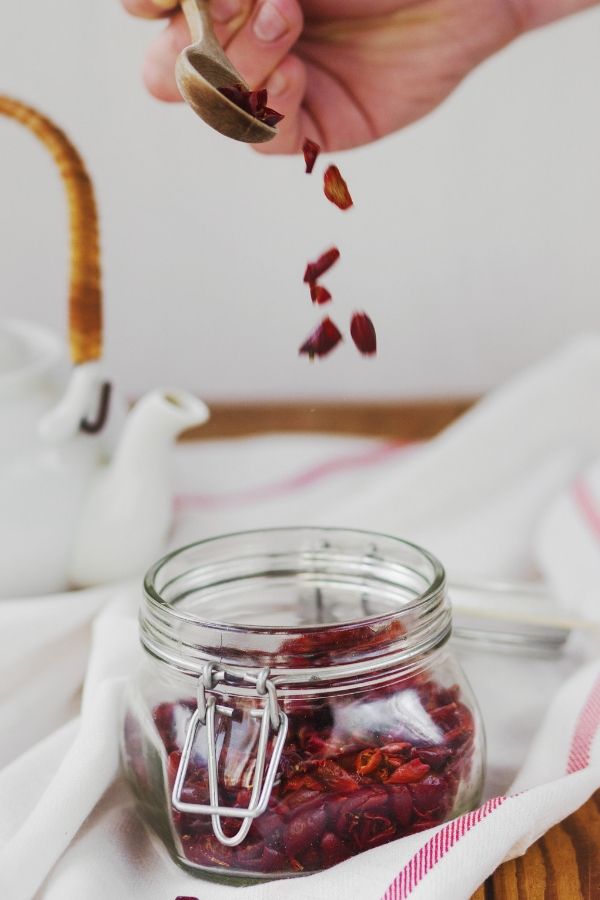 dried cranberries being spooned into a glass mason jar