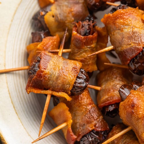 Bacon-wrapped dates, skewered by toothpicks, piled up in a large bowl.