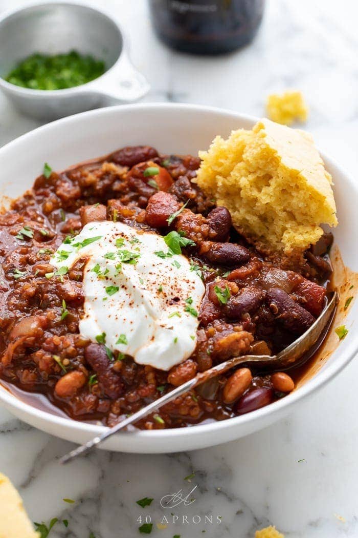 A bowl of vegan chili with a piece of cornbread