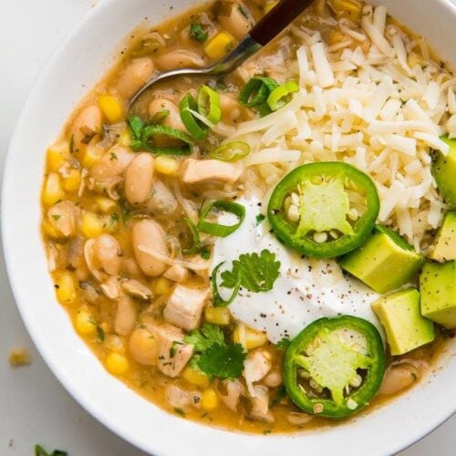 white bean chili in a white bowl with fresh toppings