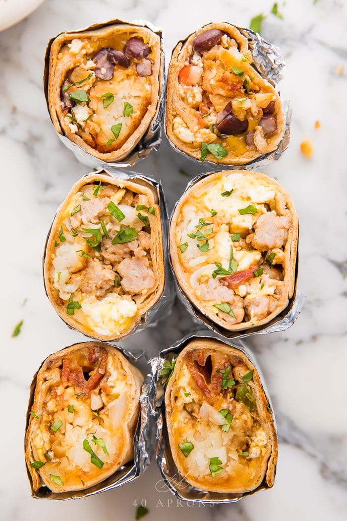 overhead shot of six healthy breakfast burritos filled with sausage, eggs and pico de gallo and vegan breakfast fillings