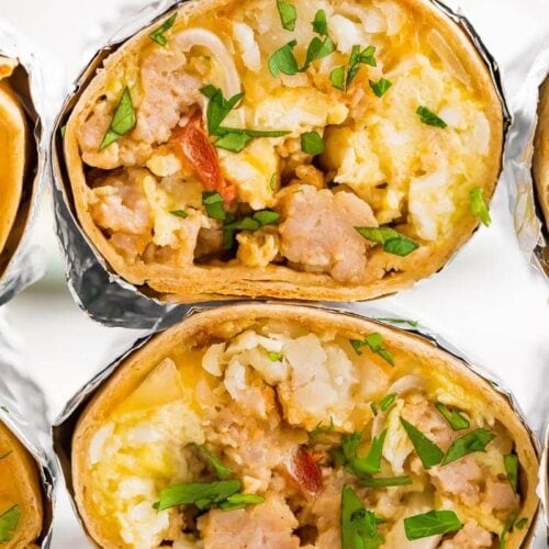 two freezer-friendly healthy whole wheat breakfast burritos with eggs, potatoes, sausage, bacon and cheese