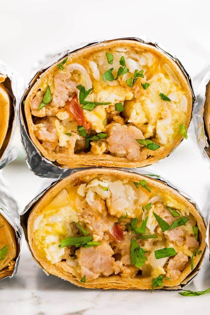 two freezer-friendly healthy whole wheat breakfast burritos with eggs, potatoes, sausage, bacon and cheese