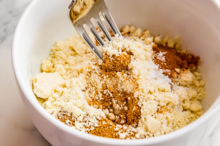 Ingredients for pumpkin muffin crumb topping in a white bowl with a fork.