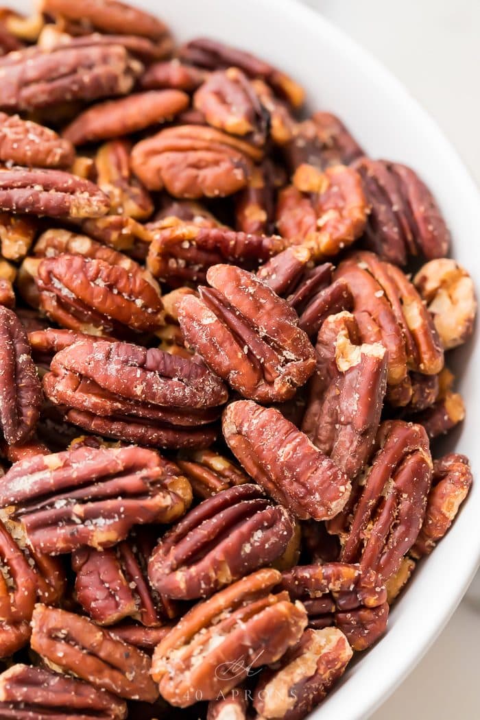 Close up of buttery toasted pecan in a white bowl