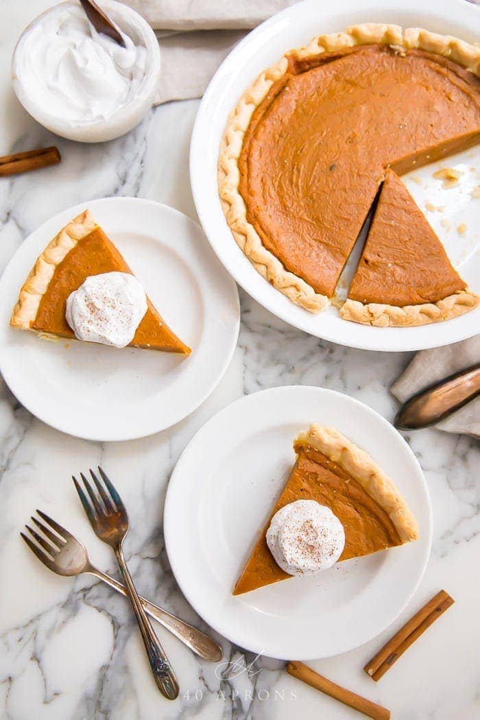 Slices of vegan pumpkin pie served with cream on white plates