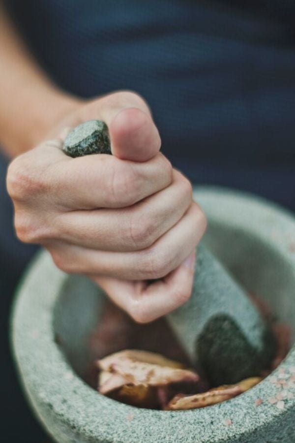 adaptogenic mushrooms being ground in a granite mortar and pestle