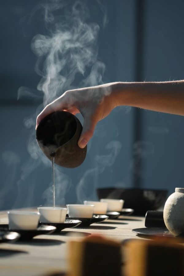 steaming hot adaptogenic tea being poured into white tea glasses