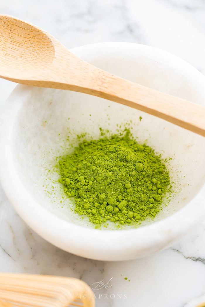 A white bowl of matcha with bamboo spoon on top