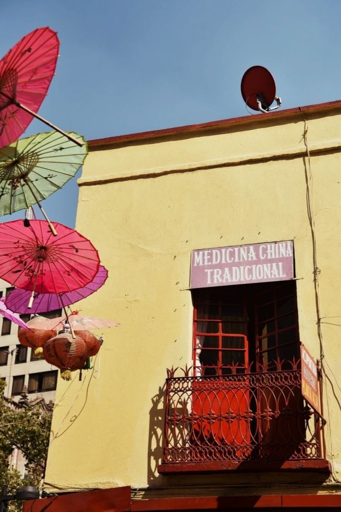 entrance door  to a traditional Chinese herb store with colorful umbrellas and paper lanterns next to it 