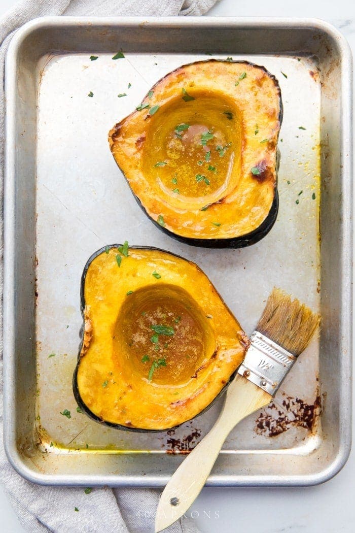 overhead shot of acorn squash on baking sheet basted with avocado oil.