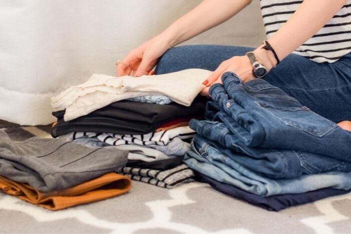 a woman sorting through her wardrobe to declutter