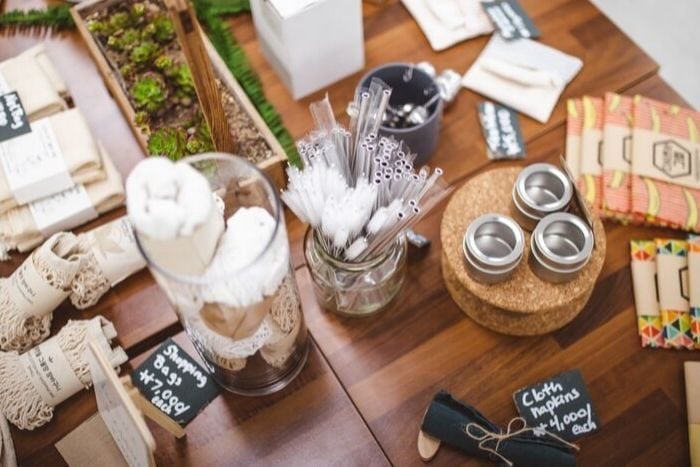 reusable food storage containers, metal straws and shopping bags displayed on the table of an eco store