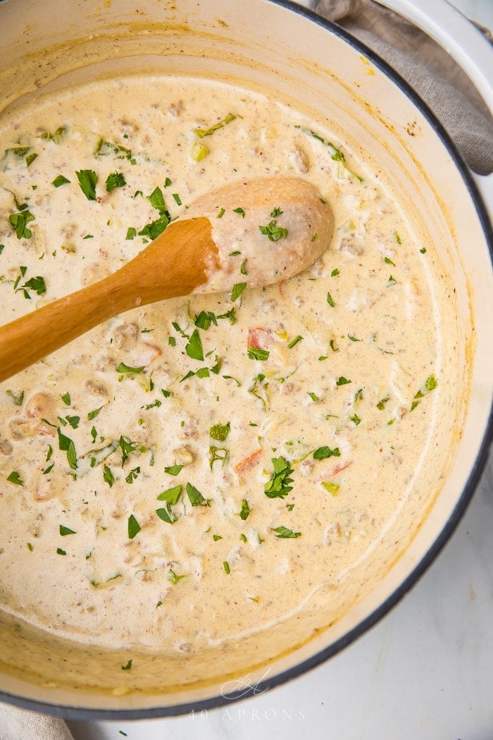 Stirring the cheeseburger soup in a pot with a wooden spoon