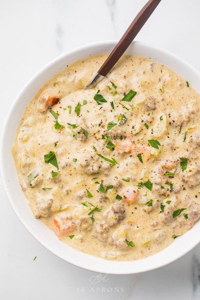 Cheeseburger soup in a white bowl with a spoon