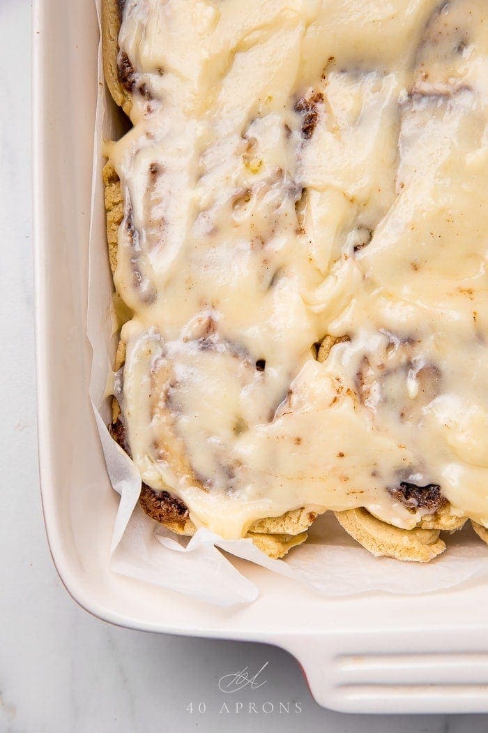 Gluten free cinnamon rolls in a baking pan with cream cheese frosting