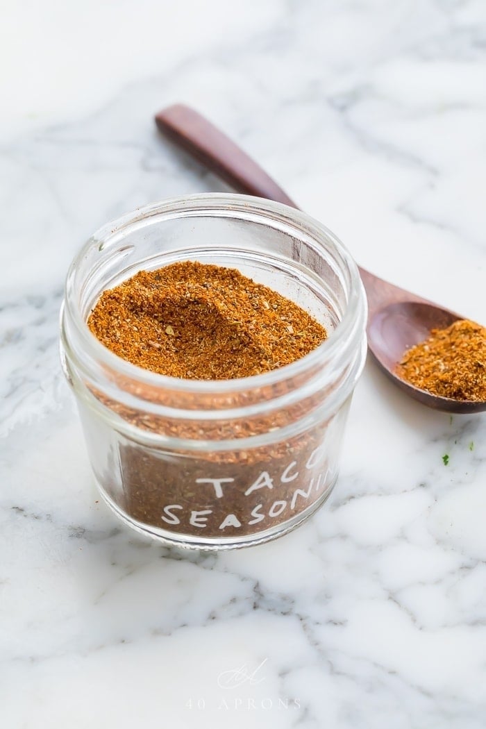 taco seasoning in a glass jar on a marble surface