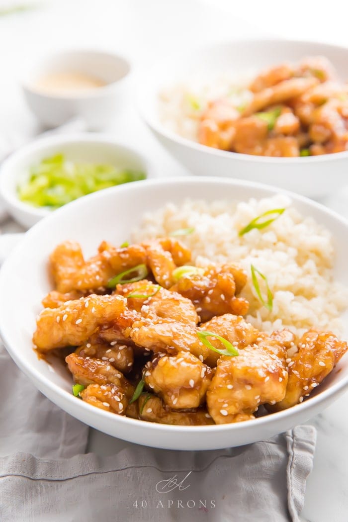 Sesame chicken served in a white bowl with cauliflower rice