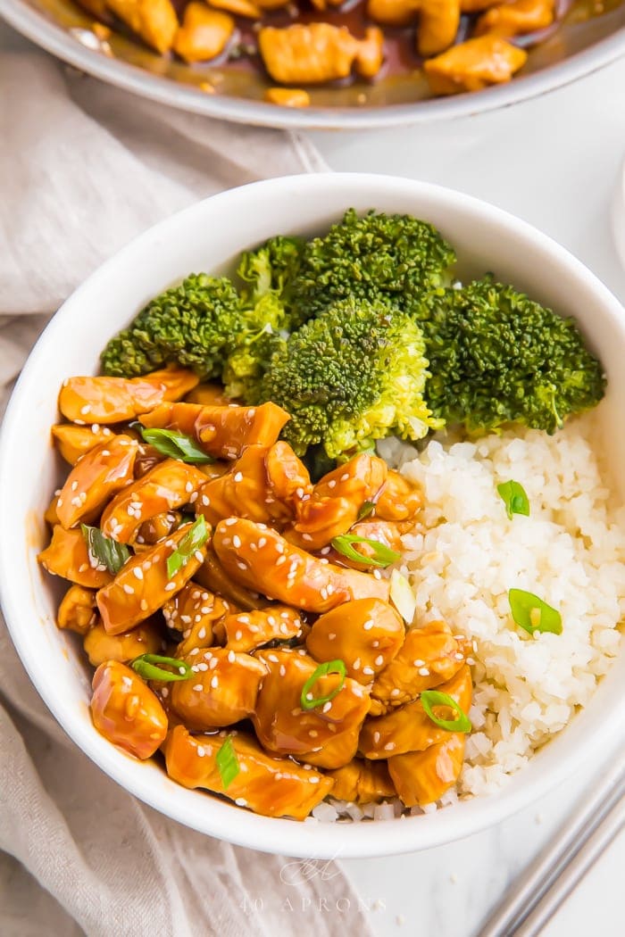 Teriyaki served in a white bowl with rice and vegetables