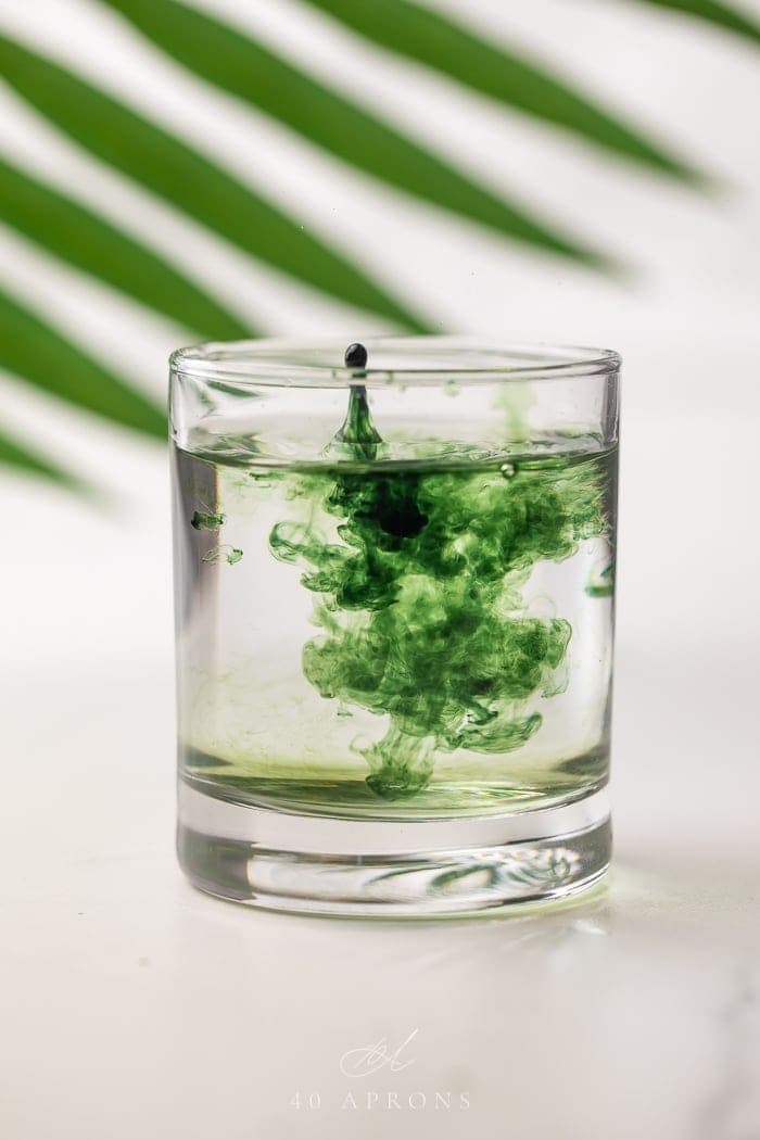 Liquid chlorophyll being dropped into a glass of water