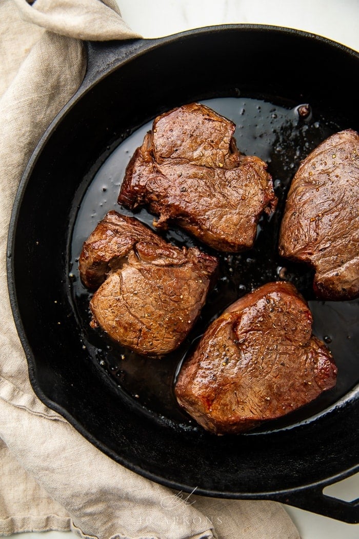 four filet mignons in cast iron skillet