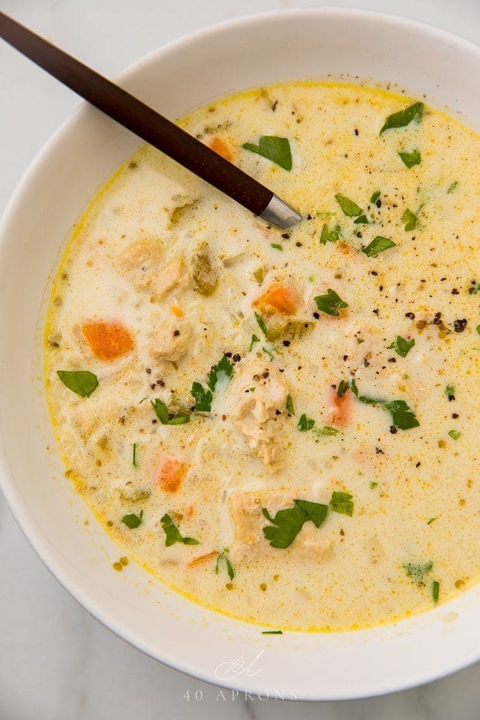 chicken and rice soup served in a white bowl with a spoon