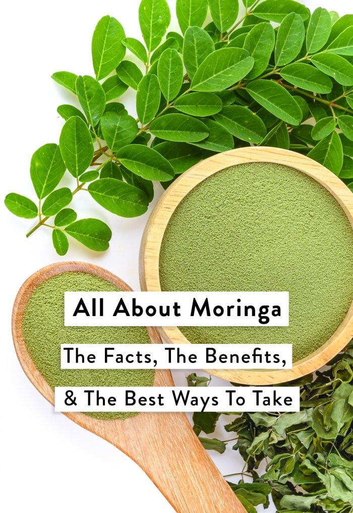 Powdered moringa in a bowl and spoon and moringa leaves