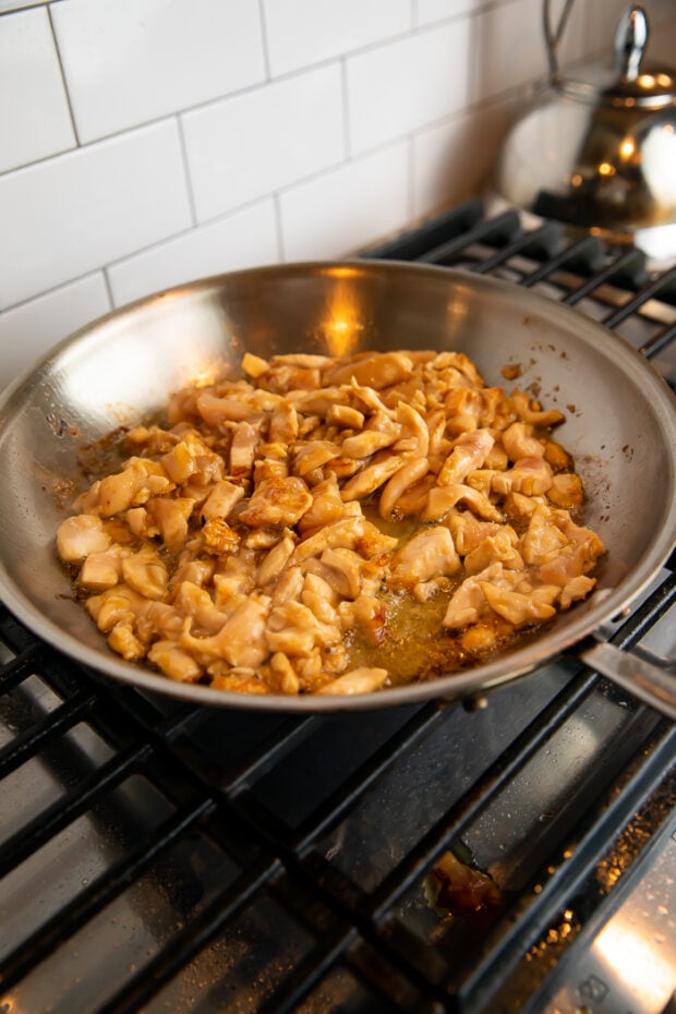 Seasoned chicken in a wok on a gas stove