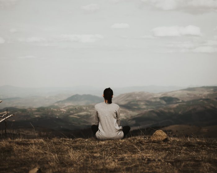 Woman sitting outside looking at mountains