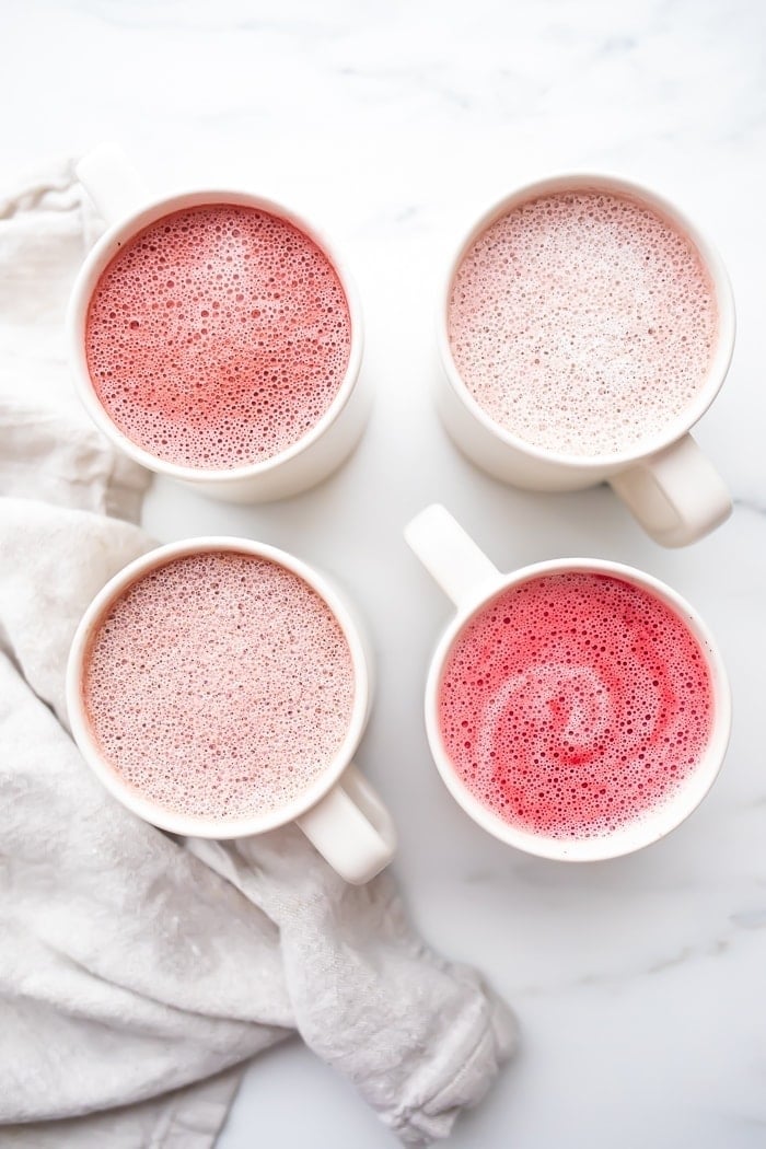 Four pink lattes in white mugs