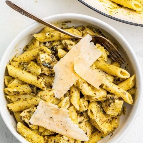 One-pot chicken pesto pasta in a bowl topped with Parmesan cheese