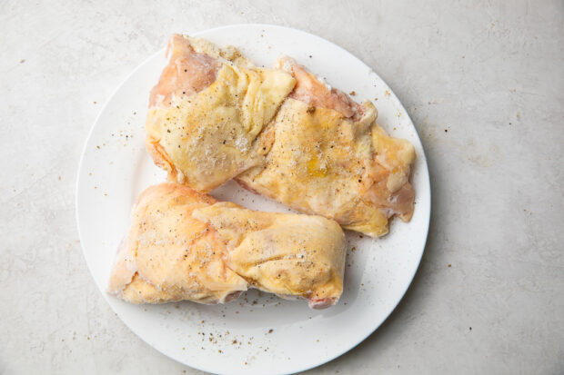 Raw chicken thighs on a white plate