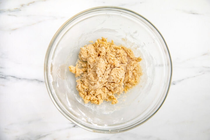 Dry ingredients added to wet ingredients in large glass mixing bowl.